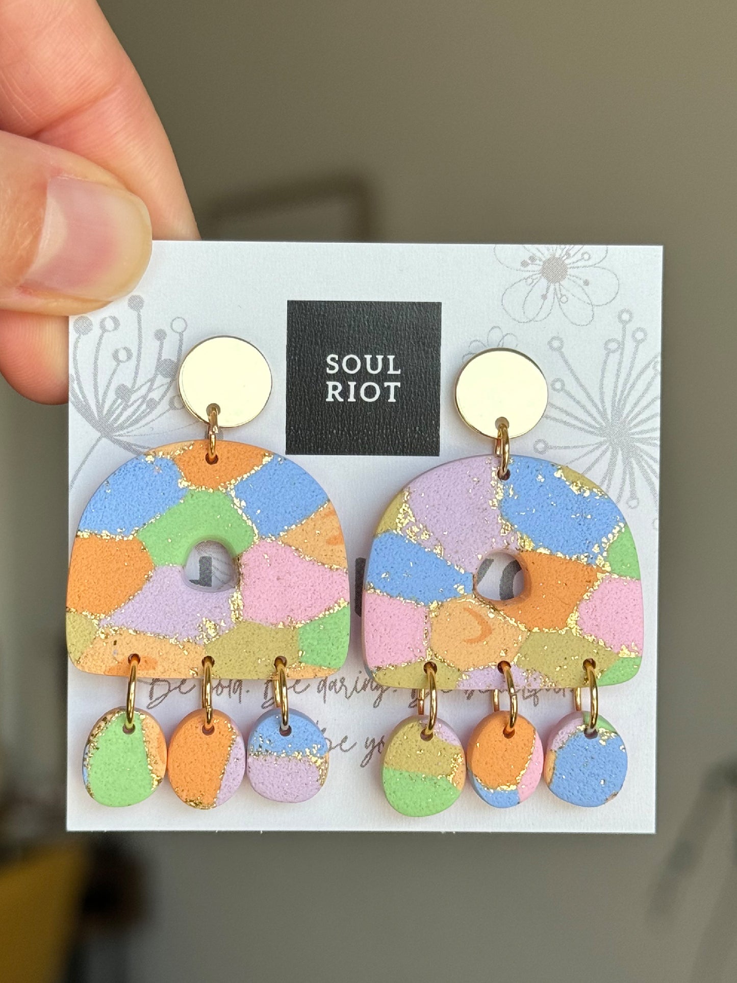 Handmade polymer clay earring with colorful pattern.